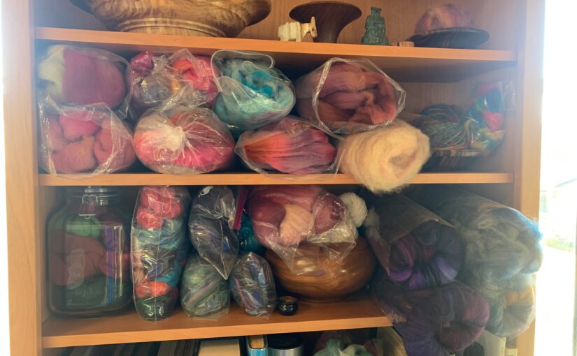 bookshelf stuffed full of a wide variety of dyed fiber, mostly in plastic bags or glass jars, waiting to be spun into yarn